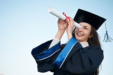 Image showing happy graduate girl looking through diploma