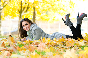 Image showing Happy student girl lying in autumn leaves with netbook