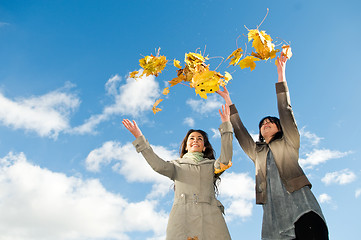 Image showing Two girls and Autumn leaves over blue sky