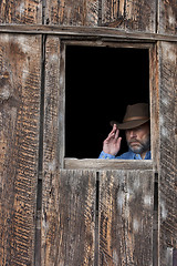 Image showing cowboy in a dark window of old barn