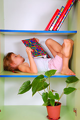 Image showing child reading a book in a bookcase