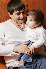 Image showing Father sitting with little daughter on sofa