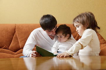 Image showing Father reading book to daughters
