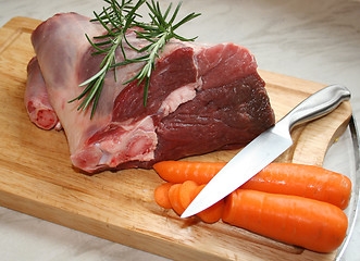 Image showing A joint of lamb ready for cooking,with carrots and rosemary