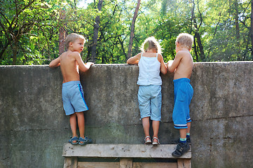 Image showing curious children spying over the fence