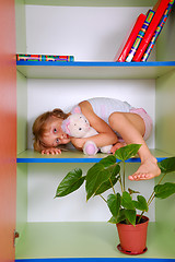Image showing child in a bookcase with a toy