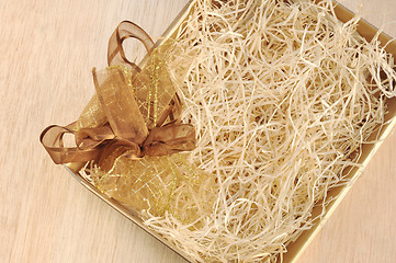 Image showing Open gift box and bow - filled with packing bast