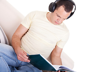 Image showing man reading and listening music with headphones on couch