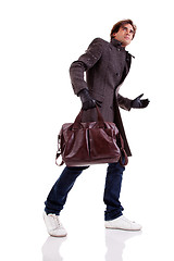 Image showing Portrait of a young man with a handbag, hasty, in autumn/winter clothes