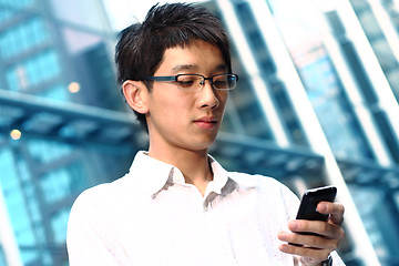 Image showing casual asian businessman texting on his cell phone