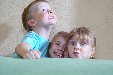 Image showing happy children hiding behind the sofa