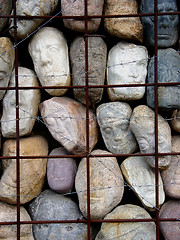 Image showing Stone faces behind the bars
