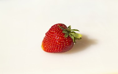 Image showing A sunlit solitary strawberry rests on a white cutting board (Macro, 14MP camera)