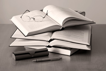 Image showing opened books pen and glasses on sepia background