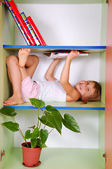 Image showing child reading a book in a bookcase