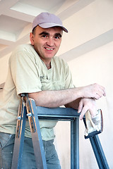 Image showing builder on a ladder with a tool