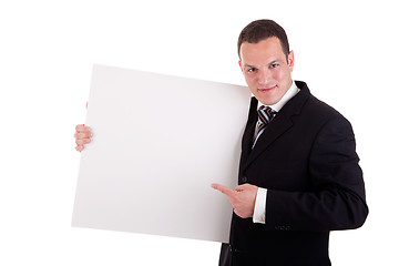 Image showing handsome businessman holding a whiteboard and pointing, looking at the camera and smiling