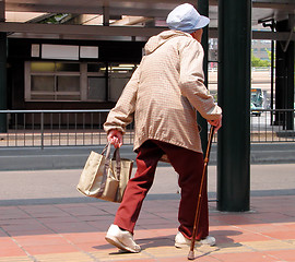 Image showing    An old woman with bag walking in a bus station-Japan