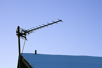 Image showing Television antenna over the snowy roof 