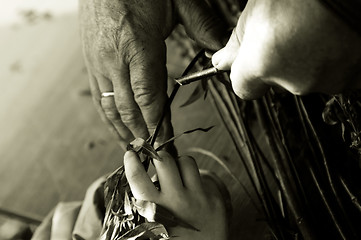 Image showing Man teaching child making a wicker basket