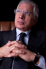 Image showing Pensive mature businessman seated on a chair, looking up