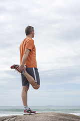 Image showing Mature runner doing exercises at a beach