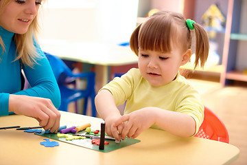 Image showing Teacher and little girl play with plasticine