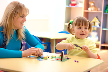 Image showing Teacher and little girl play with plasticine