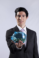 Image showing Businessman holding a piggybank full of coins