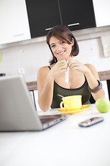 Image showing Modern woman reading e-mails at her breakfast