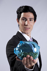 Image showing Businessman holding a piggybank full of coins