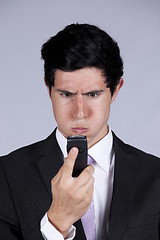 Image showing Angry businessman looking to his cellphone