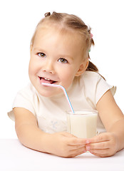 Image showing Little girl drinks milk using drinking straw