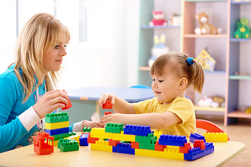 Image showing Teacher and preschooler play with building bricks