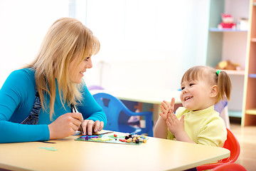 Image showing Teacher and little girl play with plasticine