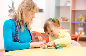 Image showing Teacher and little girl play with plasticine