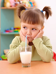 Image showing Gloomy little girl drinks milk