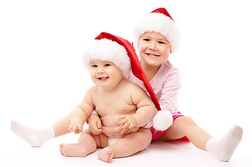 Image showing Two children wearing red Christmas caps and smile