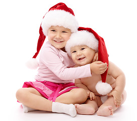 Image showing Two children wearing red Christmas caps and smile