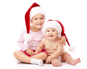 Image showing Two children wearing red Christmas caps and smile