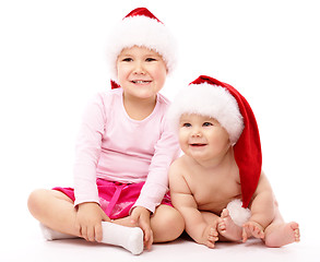 Image showing Two children wearing red Christmas caps and smile