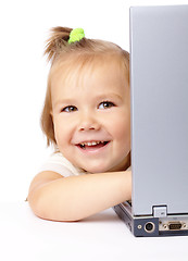 Image showing Cute little girl is looking out from her laptop