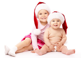 Image showing Two children wearing red Christmas caps and smile