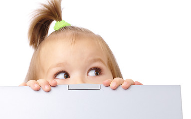 Image showing Cute little girl is looking out from her laptop