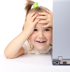 Image showing Cute little girl is looking out from her laptop