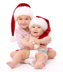 Image showing Two children wearing red Christmas caps and smile