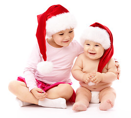 Image showing Two children wearing red Christmas caps and smile