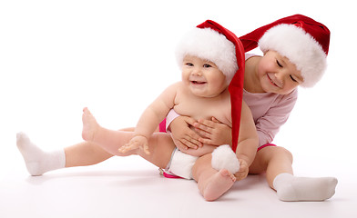 Image showing Two children wearing red Christmas caps and smile