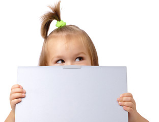 Image showing Cute little girl is looking out from her laptop