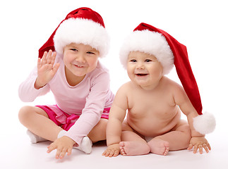 Image showing Two children wearing red Christmas caps and smile
